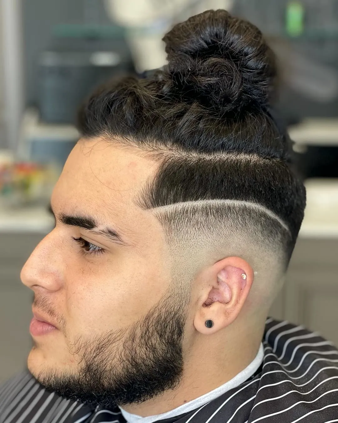 Man bun with a hard part and skin fade